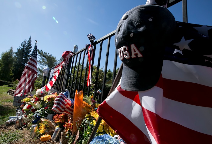 An USA hat hangs from a flag that makes up part of a memorial on the backyard fence of Las Vegas shooting victim Kurt Von Tillow Wednesday, Oct. 4, 2017, in Cameron Park, Calif. Von Tillow, 55, was at Sunday's concert with his wife, daughter, son-in-law and other family members when the shooting started, KCRA reported. (AP Photo/Rich Pedroncelli)