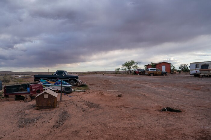 A dog sleeps on the red sand on the end of his chain at the Dinehdeal family compound in Tuba City, Ariz, on the Navajo reservation on April 20, 2020. The Dinehdeal family has been devastated by COVID-19. (AP Photo/Carolyn Kaster)