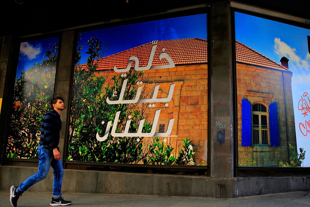 (Hassan Ammar | The Associated Press) In this Monday, April 2, 2018 photo, a bank advertisement with Arabic that reads, "Keep your home in Lebanon," is on display, in Hamra Street, in Beirut, Lebanon. Some 50 countries and international organizations are expected at the CEDRE (Cedar) conference that begins Friday, in Paris, where Beirut will request up to $22 billion for an eight to 12 year investment program as it grapples with low growth and soaring debt.