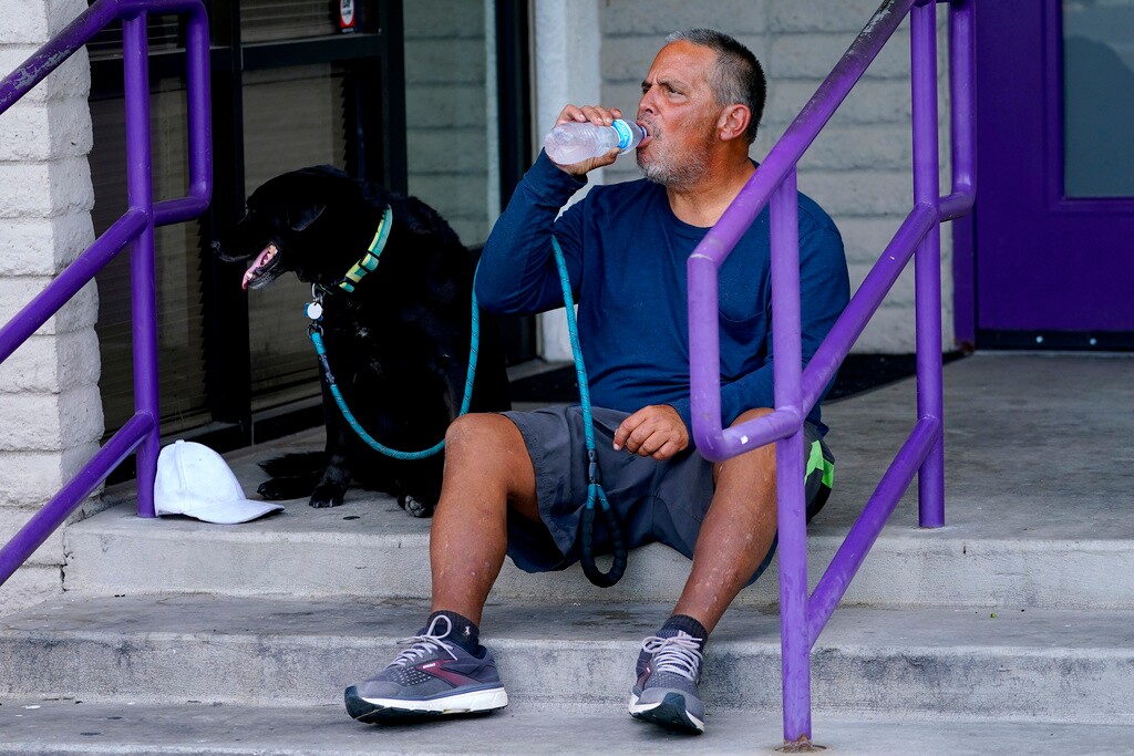 (Matt York | AP Photo) Martin Brown and his dog Sammy try to keep cool outside the Circle In The City homeless clinic, Monday, July 10, 2023, in Phoenix.