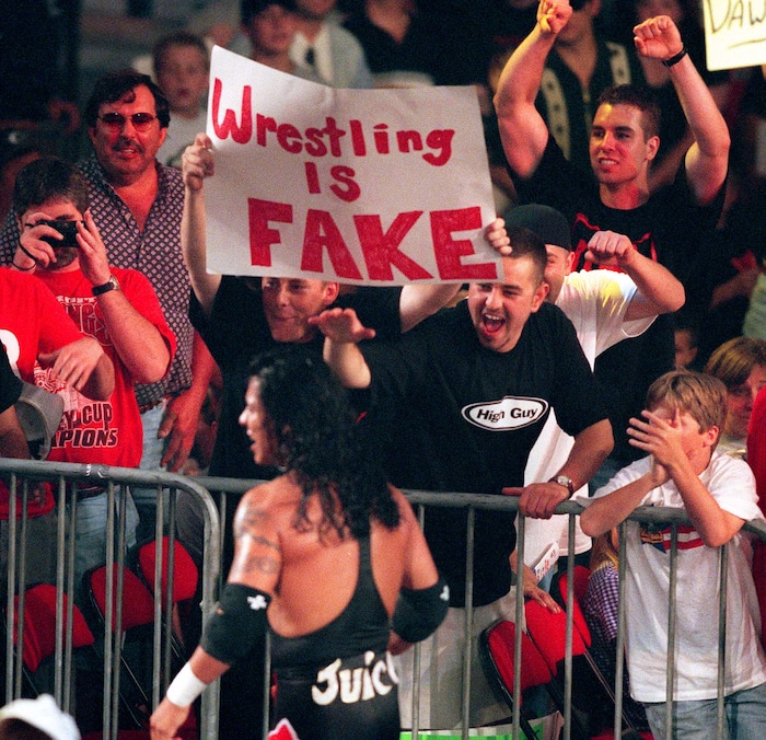(Trent Nelson | The Salt Lake Tribune) Wrestler Juventud Guerrera laughs at fans holding "wrestling is fake" sign at WCW's Bash at the Beach in San Diego. July 12, 1998.