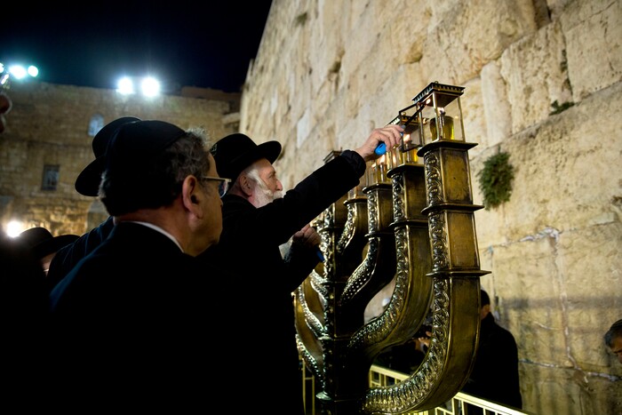 Rabbi Yitzchak Grossman lights candles on the Jewish holiday of Hanukkah at the Western Wall, the holiest site where Jews can pray in Jerusalem's Old City, Thursday, Dec. 14, 2017. (AP Photo/Sebastian Scheiner)