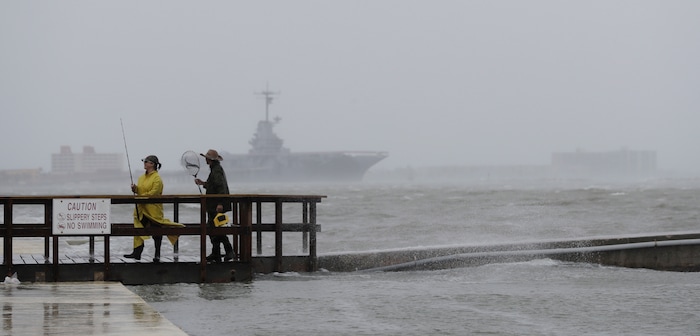 (Eric Gay | The Associated Press) Fishermen walk along a pier as the early bands of Hurricane Harvey make landfall, Friday, Aug. 25, 2017, in Corpus Christi, Texas. Harvey intensified into a hurricane Thursday and steered for the Texas coast with the potential for up to 3 feet of rain, 125 mph winds and 12-foot storm surges in what could be the fiercest hurricane to hit the United States in almost a dozen years.