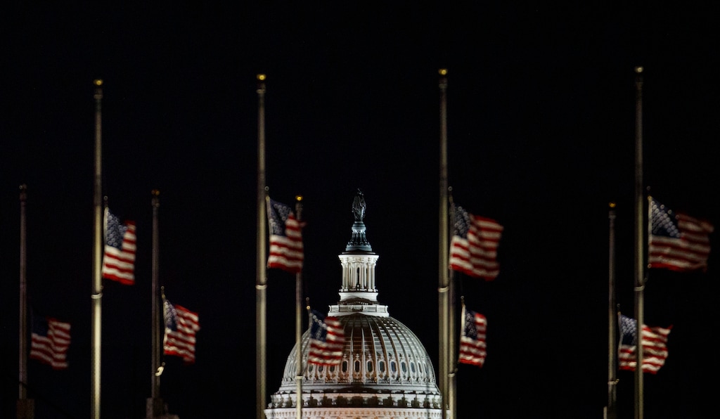 The U.S. Capitol Dome is seen beyond American Flags around the the base of the Washington Monument in Washington, early Saturday, Dec. 22, 2018. The American Flags are at half-staff to honor of former President George H.W. Bush. Hundreds of thousands of federal workers faced a partial government shutdown early Saturday after Democrats refused to meet President Donald Trump's demands for $5 billion to start erecting a border wall with Mexico. Overall, more than 800,000 federal employees would see their jobs disrupted, including more than half who would be forced to continue working without pay. (AP Photo/Carolyn Kaster)