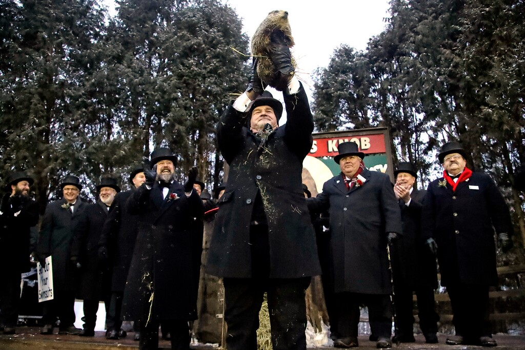(AP Photo/Gene J. Puskar) Groundhog Club co-handler John Griffiths, center, holds Punxsutawney Phil, the weather prognosticating groundhog, during the 133rd celebration of Groundhog Day on Gobbler's Knob in Punxsutawney, Pa. Saturday, Feb. 2, 2019. Phil's handlers said that the groundhog has forecast an early spring.