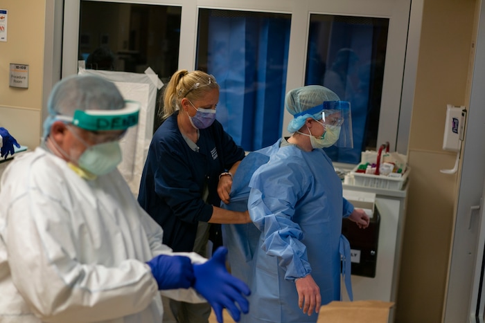 Team Rubicon Volunteers Dennis Grooms, an EMT from St. Louis, left, nurse Cindy Robison, a U.S. Air Force veteran from Colorado Springs, Colo., and EMT Tracy Thomas from Omaha, Neb., prepare to see a coronavirus patient in the emergency room of the Kayenta Health Center in Kayenta, Ariz., on April 23, 2020. The Navajo reservation has some of the highest rates of coronavirus in the country. Team Rubicon is helping with medical operations as cases of COVID-19 surge. (AP Photo/Carolyn Kaster)