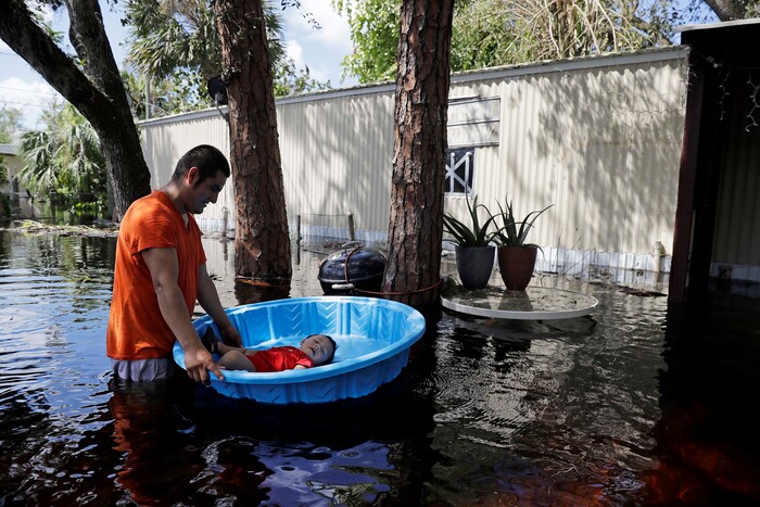 Jose Lopez floats his son Jose Jr, 1, in a splash pool as they retrieve belongings from their flooded home following Hurricane Irma in Bonita Springs, Fla., Tuesday, Sept. 12, 2017. (AP Photo/David Goldman)