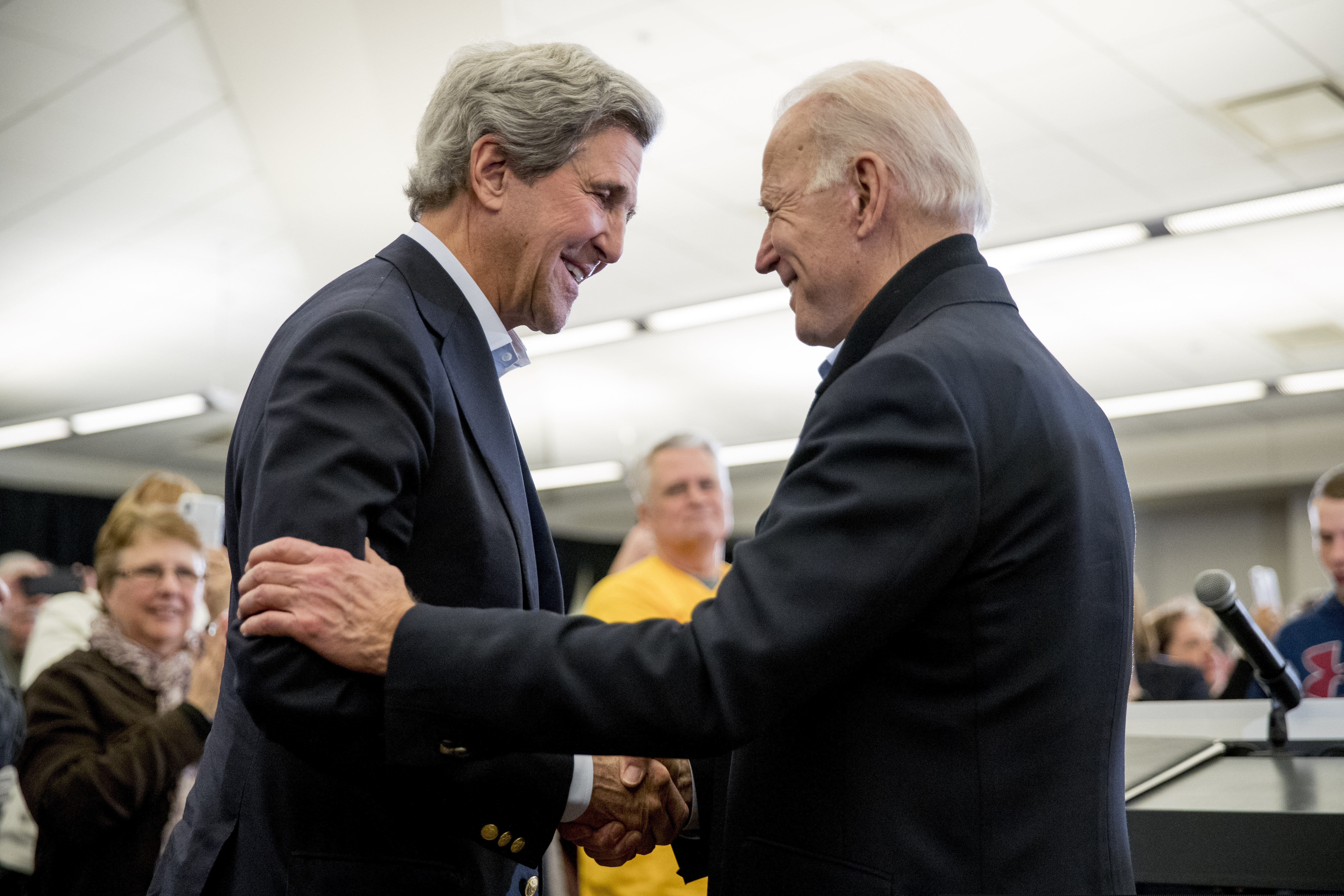 (Andrew Harnik | AP file photo) Former Vice President Joe Biden smiles as former Secretary of State John Kerry, left, takes the podium to speak at a campaign stop at the South Slope Community Center in North Liberty, Iowa, Feb. 1, 2020.