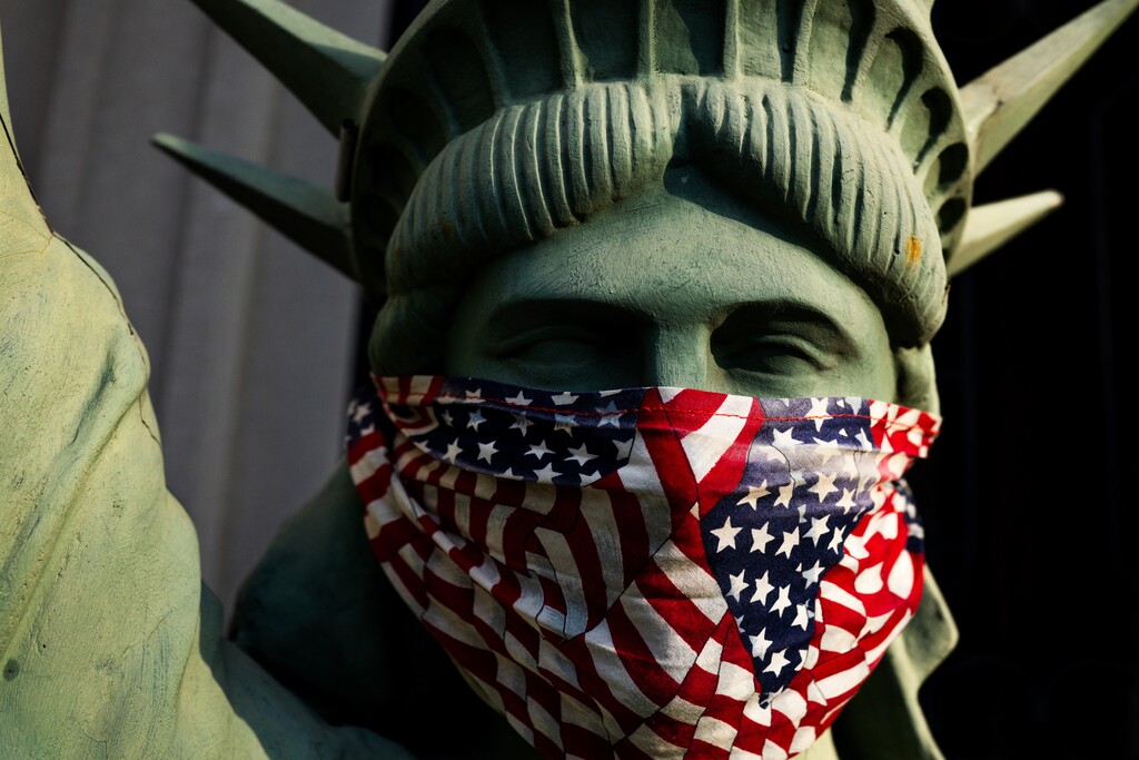 (Demetrius Freeman | The New York Times) A masked mini Statue of Liberty on the front porch of a home in Brooklyn, N.Y., on Tuesday,  April 7, 2020.