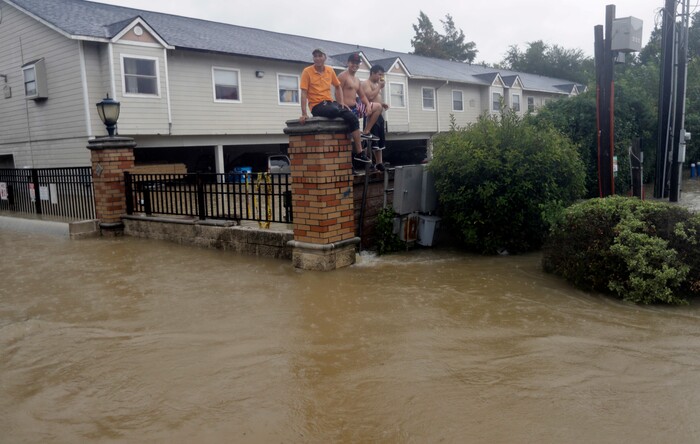(David J. Phillip | The Associated Press) Residents sit on a fence surrounded by floodwaters from Tropical Storm Harvey on Sunday, Aug. 27, 2017, in Houston, Texas.