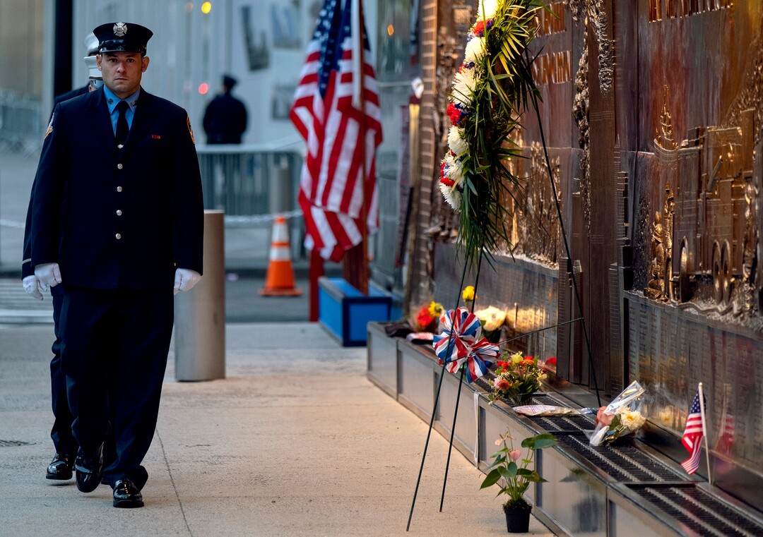 (Craig Ruttle | AP Photo) New York City firefighters take a position in front of a memorial on the side of a firehouse adjacent to One World Trade Center and the 9/11 Memorial site during ceremonies commemorating the 18th anniversary of the 9/11 terrorist attacks in New York on Wednesday, Sept. 11, 2019.