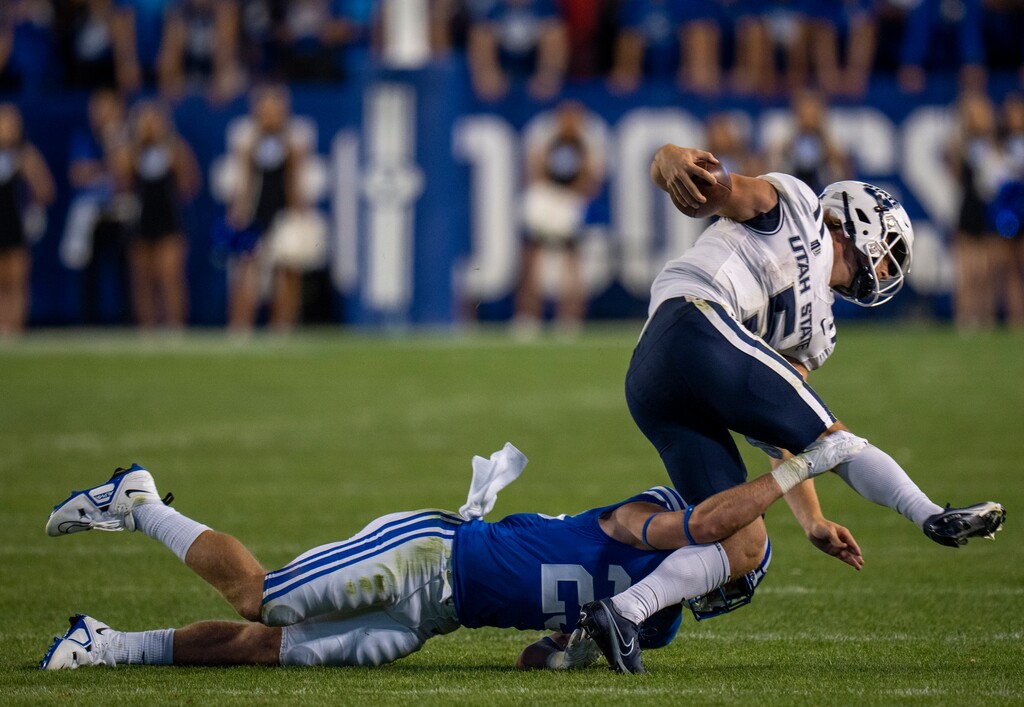 (Rick Egan | The Salt Lake Tribune) Brigham Young Cougars defensive back Talan Alfrey (25) brings down Utah State Aggies quarterback Cooper Legas (5) at LaVell Edwards Stadium in Provo, on Sept. 29, 2022.