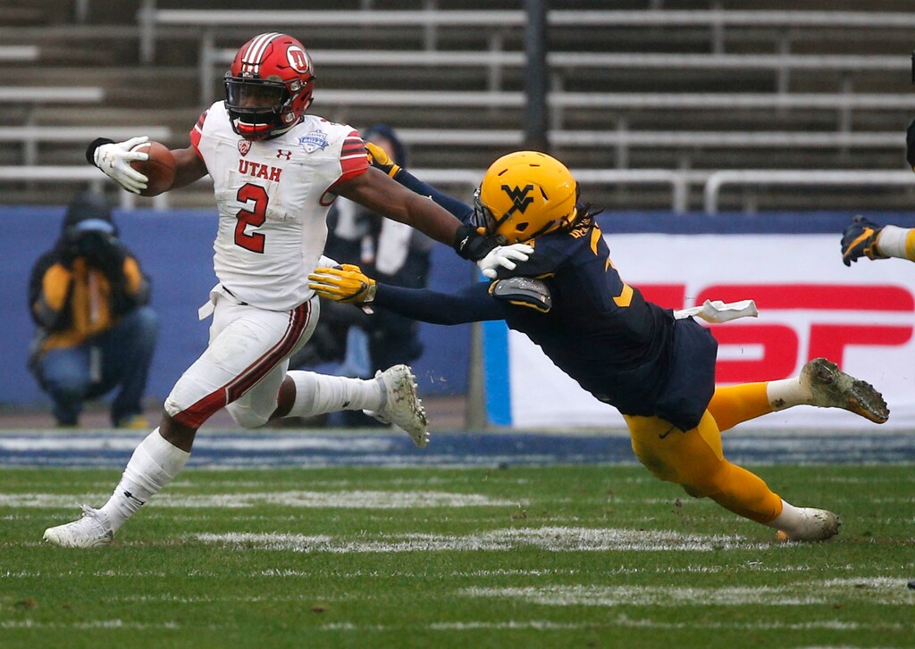 Utah running back Zack Moss (2) stiff-arms West Virginia Mountaineers linebacker Al-Rasheed Benton (3) while running the ball during the third quarter of Zaxby's Heart of Dallas Bowl NCAA college football game in Dallas on Wednesday, Dec. 26, 2017. Utah won 30-14. (Rose Baca/The Dallas Morning News via AP)