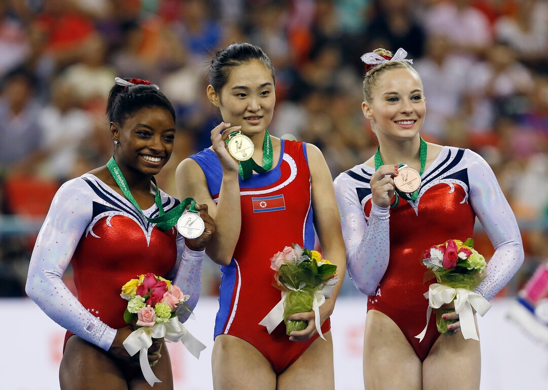 Gold medalist Hong Un Jong of North Korea, center, second place Simone Biles of the U.S., left, and third place Mykayla Skinner of U.S. pose for photos on podium during the award ceremony of the women's vault apparatus final of the Artistic Gymnastics World Championship at the Guangxi Gymnasium in Nanning, capital of southwest China's Guangxi Zhuang Autonomous Region Saturday, Oct. 11, 2014. (AP Photo/Andy Wong)