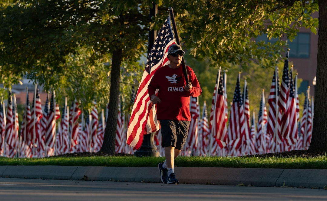 (Francisco Kjolseth | The Salt Lake Tribune) Master Sergeant Colin Green, a veteran of Kuwait, Iraq and Afghanistan runs the American flag as the sun rises on Saturday, Sept. 11, 2021, at the Utah Healing Field in Sandy, part of the nonprofit Colonial Flag Foundation, who posted 3,000 flags to honor the fallen. The display is free to the public and open now through Sept. 13.