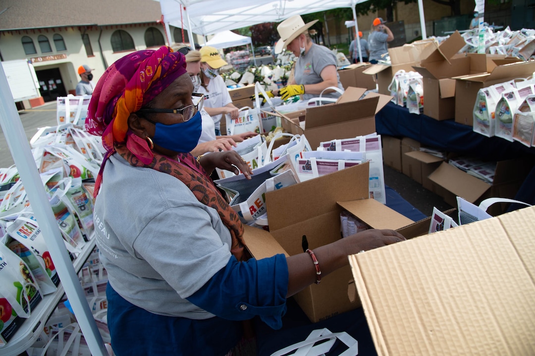 (Francisco Kjolseth  |  The Salt Lake Tribune) Habiba Nur helps assemble food bags as the third “Miracle Project” for the nonprofit foundation which raises money to purchase food produced by Utah farmers and then gives to residents in need, takes place at the Utah State Fairpark in Salt Lake City on Monday, July 27, 2020. The food donation from the Utah Farm Bureau’s “Farmers Feeding Utah” program provided food for 600 individuals and families who have recently become unemployed due to the coronavirus.