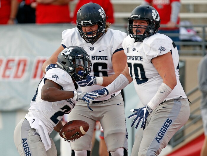 Utah State running back LaJuan Hunt, left, celebrates with teammates Rob Castaneda, right, and Roman Andrus after scoring a touchdown during the first half of an NCAA college football game against New Mexico in Albuquerque, N.M., Saturday, Nov. 4, 2017. (AP Photo/Andres Leighton)