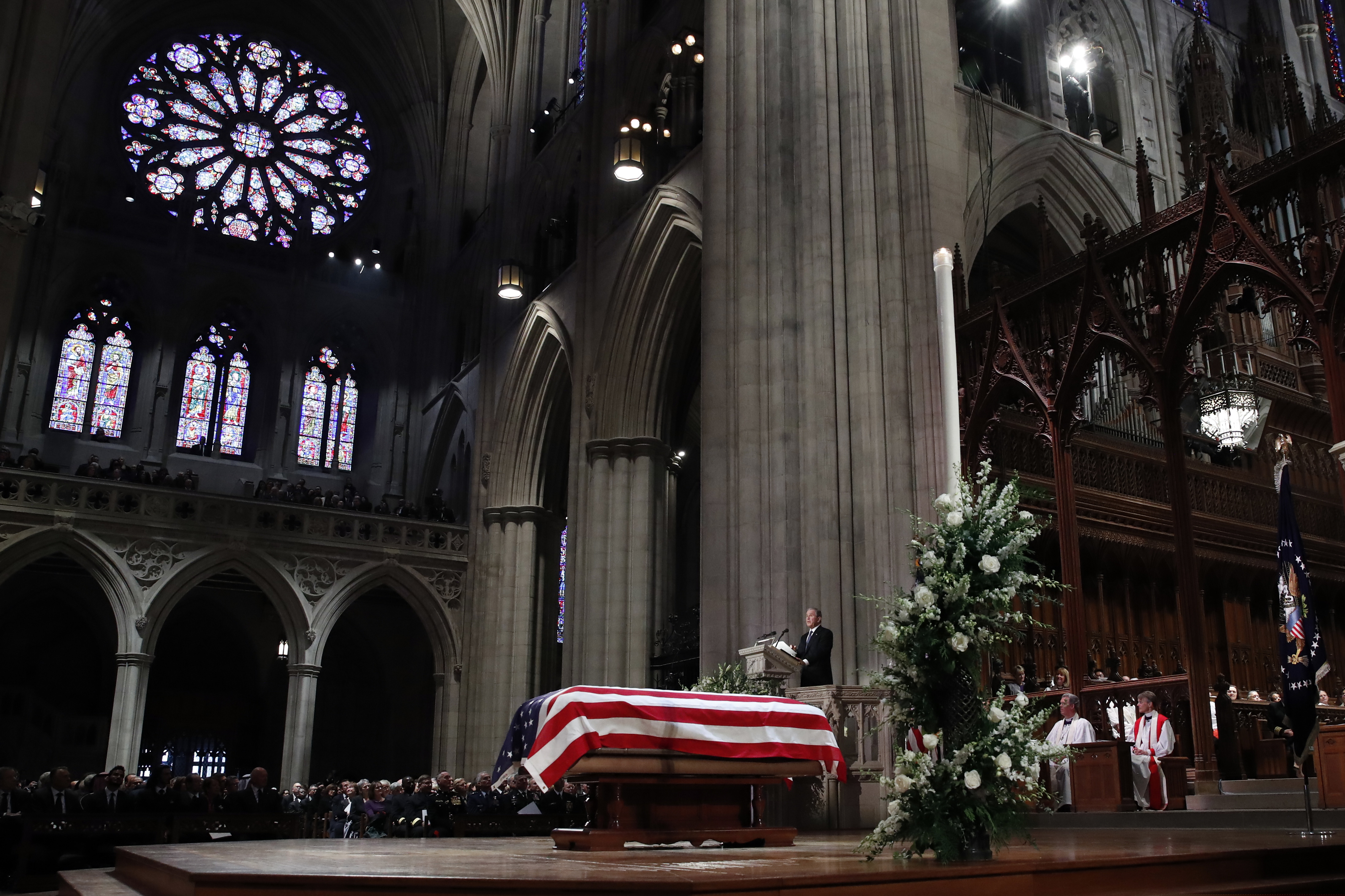 Former President George W. Bush speaks in front of the flag-draped casket of his father, former President George H.W. Bush, at the State Funeral at the National Cathedral, Wednesday, Dec. 5, 2018, in Washington. (AP Photo/Alex Brandon, Pool)