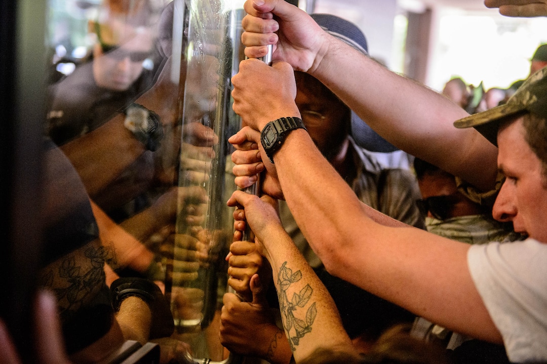 (Trent Nelson  |  The Salt Lake Tribune)  Police struggle with protesters for control of a door at the Chamber of Commerce Building Salt Lake City on Tuesday, July 9, 2019. Dozens of people showed up to protest the proposed Inland Port and ended up clashing with police, resulting in temporary street closures and arrests.
