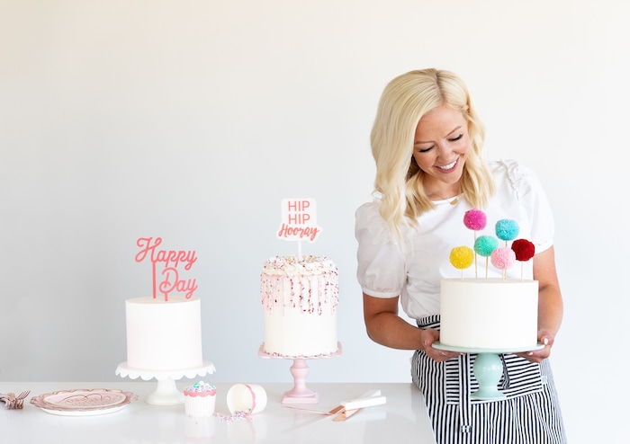 (Photo by Trina Harris Photography | Courtesy of Courtney Rich) Courtney Rich poses with some cakes she made featuring cake toppers and other products from her collection with My Mind's Eye.