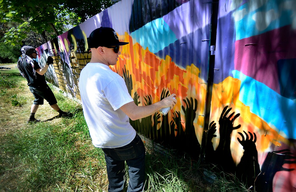 (Scott Sommerdorf | Tribune file photo)
Justin Johnson, left and Ryan Worwood put the finishing touches on their panels as local artists with Justified Ink worked together with Glendale Middle School students to install a mural on a length of fence next to the Jordan Parkway Trail, June 2, 2017.
