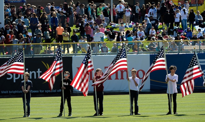 (Francisco Kjolseth  |  The Salt Lake Tribune)  Kids stand with the national flag during the playing of the national anthem before the start of the Bee's game at Smith's Ballpark in Salt Lake City for the annual annual kids day game on Thursday, May 2, 2019.