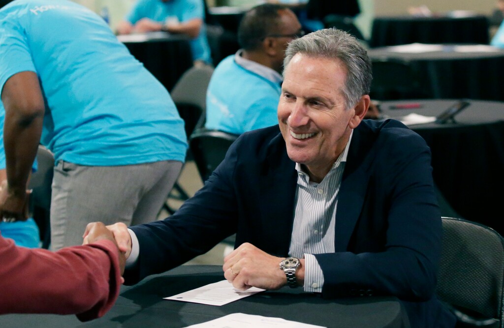 FILE - In this May 19, 2017, file photo, Starbucks CEO Howard Schultz, right, shakes hands with a job seeker during the Opportunity Fair and Forum employment event in Dallas. For someone who has given about $150,000 to Democratic campaigns over the years, Schultz is generating tepid, or even hostile, responses within the party as he weighs a presidential bid in 2020. That's because reports have suggested he's considering running as an independent, a prospect that could draw support away from the eventual Democratic nominee and hand President Donald Trump another four years in office, many fret. (AP Photo/LM Otero, File)