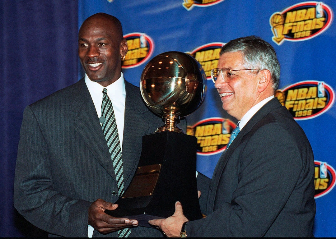 (Charles Bennett | AP File) In this June 18, 1996 photo, Chicago Bulls' Michael Jordan, left, receives the NBA Finals Most Valuable Player trophy from Commissioner David Stern during a ceremony in Chicago. David Stern, who spent 30 years as the NBA's longest-serving commissioner and oversaw its growth into a global power, has died on New Year’s Day, Wednesday, Jan. 1, 2020. He was 77.