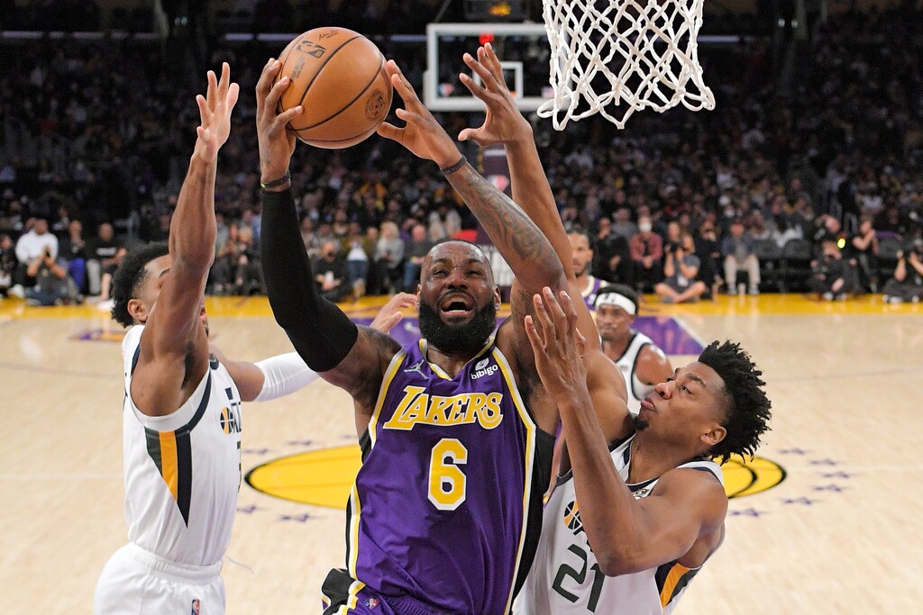 Los Angeles Lakers forward LeBron James, center, shoots as Utah Jazz guard Trent Forrest, left, and center Hassan Whiteside defend during the first half of an NBA basketball game Wednesday, Feb. 16, 2022, in Los Angeles. (AP Photo/Mark J. Terrill)