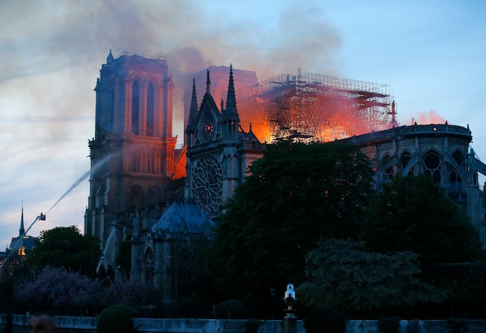 A firefighter tackles the blaze as flames and smoke rise from Notre Dame cathedral as it burns in Paris, Monday, April 15, 2019. Massive plumes of yellow brown smoke is filling the air above Notre Dame Cathedral and ash is falling on tourists and others around the island that marks the center of Paris. (AP Photo/Michel Euler)