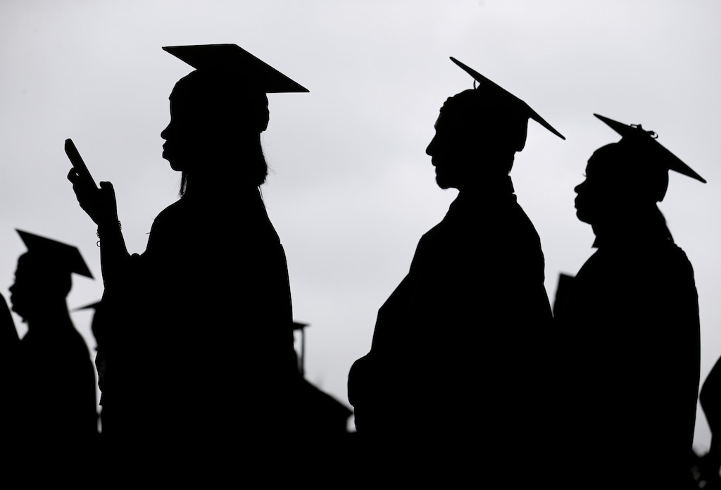 (Seth Wenig | The Associated Press) New graduates line up before the start of a community college commencement on May 17, 2018. 