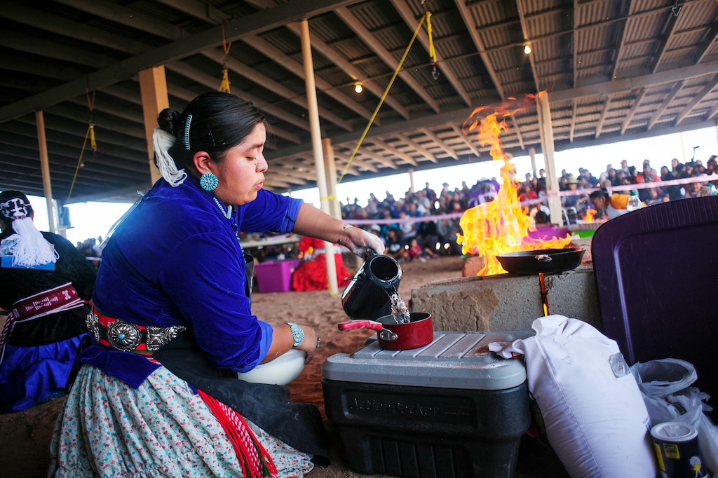 CORRECTS TO ARIZONA - In this undated photo Miss Navajo Pageant contestant Wallita Begay pours water to mix with Blue Bird flour during the fry bread competition at the Navajo Nation Fairgrounds in Window Rock, Ariz. The Miss Navajo Nation pageant is parting ways with fry bread, the fluffy, golden brown delicacy that’s become a symbol of Native American culture but is rooted in oppression. Women vying for the crown this week in Window Rock will prepare traditional Navajo foods instead, like blue corn mush or a cake made at puberty ceremonies. (Adron Gardner/Gallup Independent via AP)