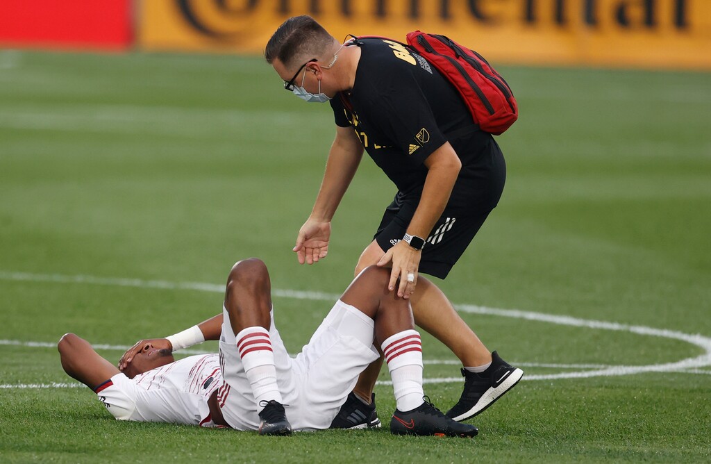 Real Salt Lake forward Douglas Martinez, left, is tended to by a trainer after taking a kicked ball to the head in the first half of an MLS soccer match against the Colorado Rapids, Saturday, Aug. 22, 2020, in Commerce City, Colo. (AP Photo/David Zalubowski)