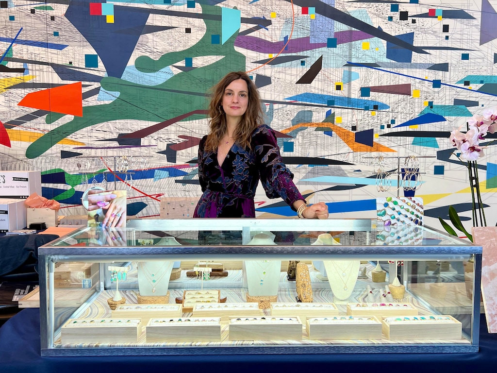 (Emily Amey Jewelry) Emily Amey, who has a studio in New York's Hudson Valley and has sold her jewelry through the Sundance catalog, poses for a photo behind a display of some of her work.