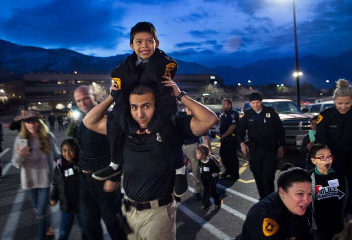 (Scott Sommerdorf   |  The Salt Lake Tribune)   Officer William Caycho carries Carlos Clemente on his shoulders on their way to see Santa who had just arrived at the first ever Police Pay It Forward event, Saturday, December 16, 2017.  