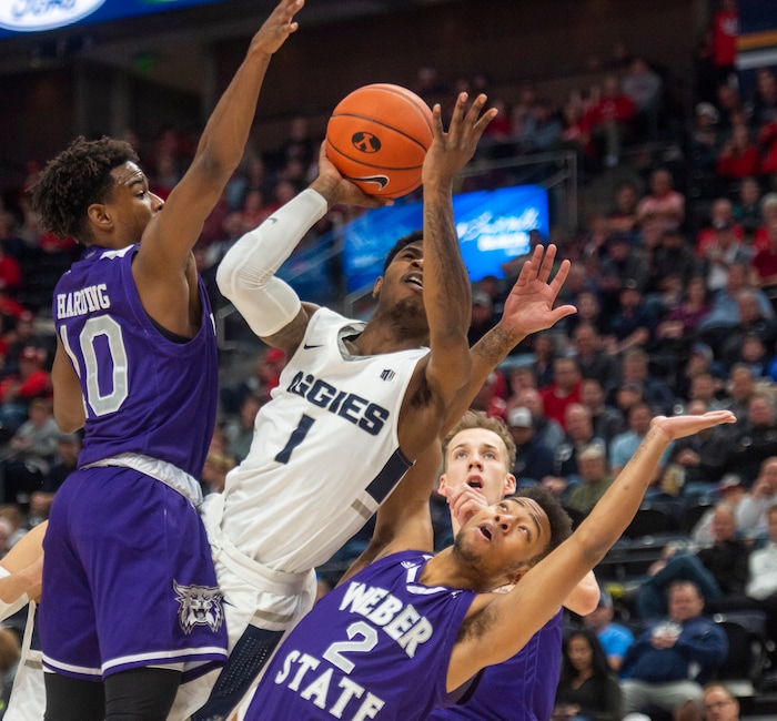 (Rick Egan  |  The Salt Lake Tribune)   Utah State Aggies guard Tauriawn Knight (1) shoots as Weber State Wildcats guard Jerrick Harding (10) and Weber State Wildcats guard Ricky Nelson (2) defend,  in basketball action in the Beehive Classic, between against the Utah State Aggies and Weber State Wildcats, a the Vivint Smart Home Arena, Saturday December 8, 2018.

 