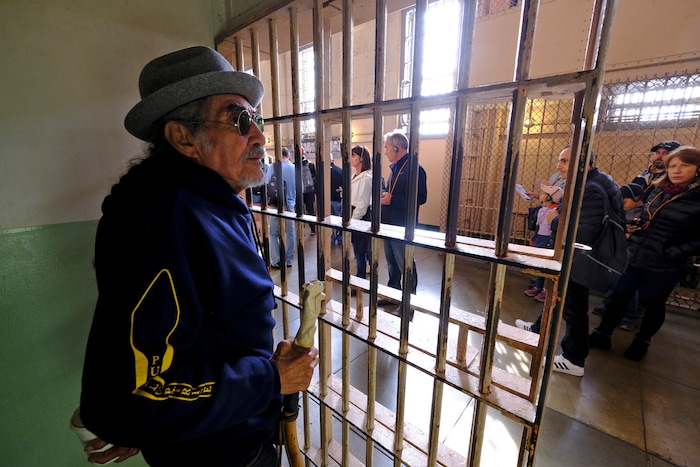 (Eric Risberg | AP) In this photo taken Tuesday, Nov. 12, 2019, Eloy Martinez, who took part in the Native American occupation of Alcatraz 50 years earlier, stands in the cell that he used to sleep in and looks out at tourists visiting the island in San Francisco. The week of Nov. 18, 2019, marks 50 years since the beginning of a months-long Native American occupation at Alcatraz Island in the San Francisco Bay. The demonstration by dozens of tribal members had lasting effects for tribes, raising awareness of life on and off reservations, galvanizing activists and spurring a shift in federal policy toward self-determination.