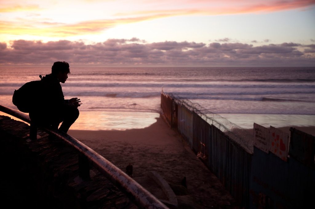 FILE- In this Wednesday, Jan. 9, 2019, file photo a man looks towards where the border wall meets the Pacific Ocean in Tijuana, Mexico. With the standoff over paying for his long-promised border wall dragging on, the president’s Oval Office address and visit to the Texas border over the past week failed to break the logjam and left aides and allies fearful that the president has misjudged Democratic resolve and is running out of negotiating options. (AP Photo/Gregory Bull, File)