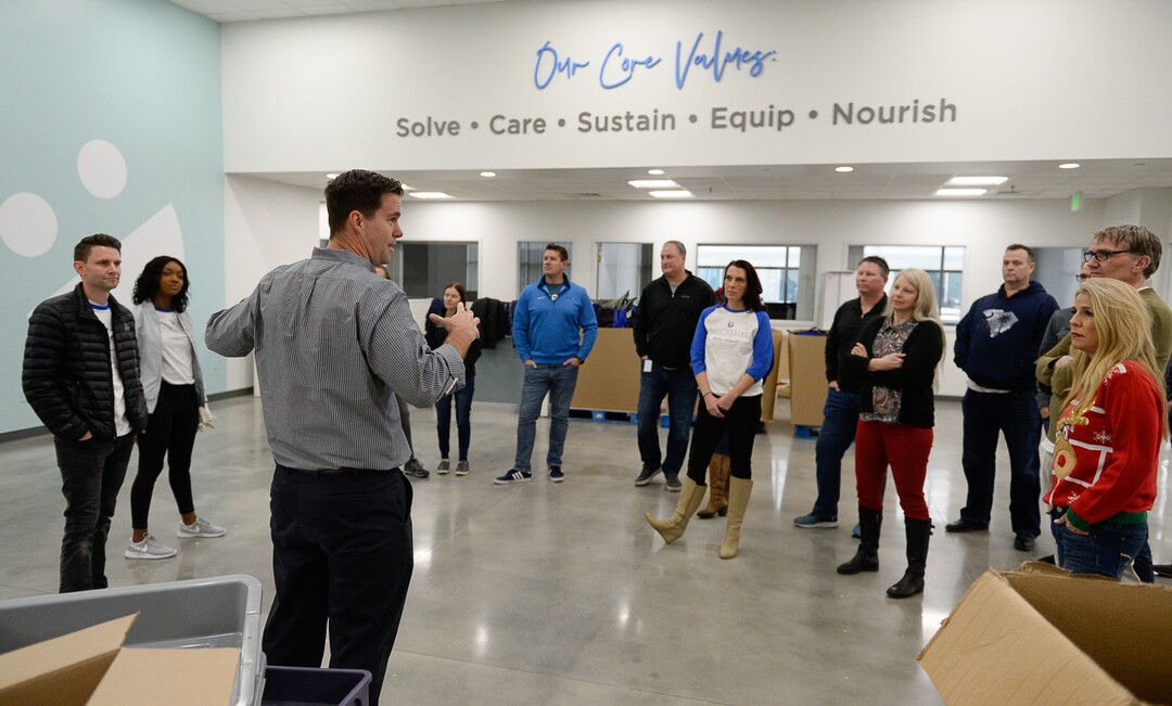 (Francisco Kjolseth  |  The Salt Lake Tribune)  Brian Paul, Pres. of the USANA Foundation gathers a team of staff volunteers before a session assembling food bags for at-risk youth at the newly-renovated packing and storage facility next to the headquarters of the Salt Lake City company on Wed. Dec. 11, 2019. The USANA Foundation has acquired two local charities, Kids Next Door and KidsEat!, that provides hundreds of food bags every week for the kids for the weekends and during long school breaks.