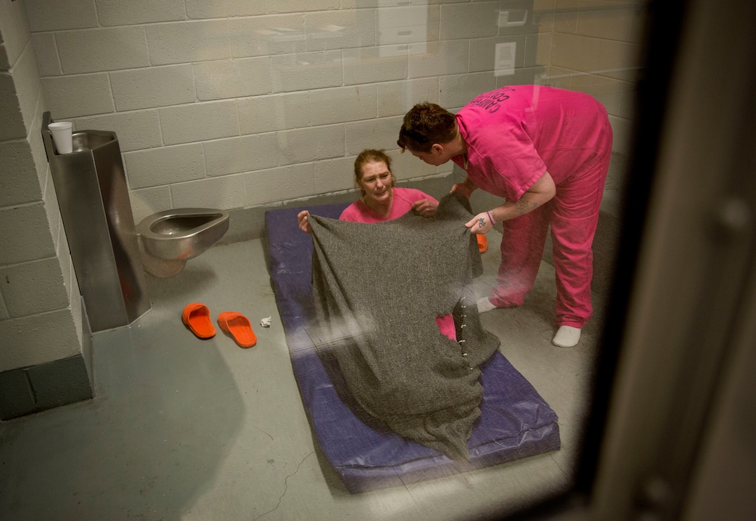 Inmate Mary Sammons, 41, right, helps cover Linda Green, 51, with a blanket as she lies down in the Campbell County Jail after being arrested on charges of public intoxication, a parole violation, in Jacksboro, Tenn., Thursday, March 29, 2018. Green first got hooked on drugs when she was given Xanax over 20 years ago during a custody battle to keep her kids. She says she used to shoplift to support them. "It was either sell my body or steal from a store and I'm not one to sell my body. I had to do what I had to do," said Green. "When I had my kids, I stole to support my children. After I lost them I stole to support my drug habit." (AP Photo/David Goldman)