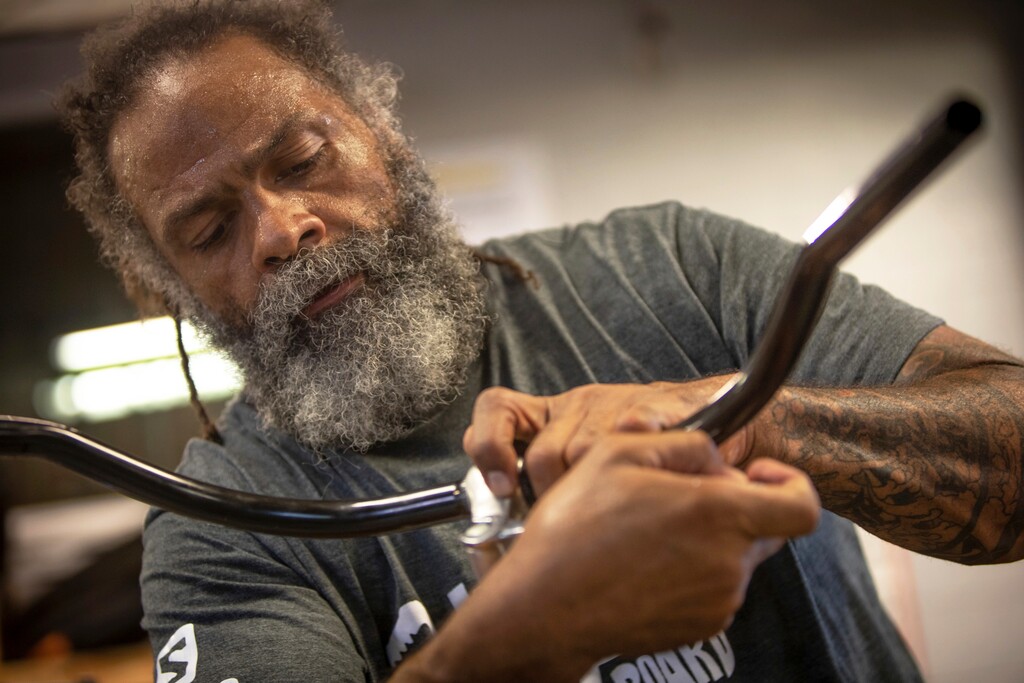 In this Tuesday, Aug. 7, 2018 photo, Mark Johnson attaches new handlebars to one of his homemade bikes at the Ogden Bicycle Collective in Ogden, Utah. Johnson took mechanic classes at the non-profit bike collective before he started building his own bicycles. (Benjamin Zack/Standard-Examiner via AP)