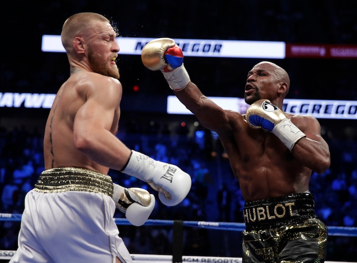 Floyd Mayweather Jr. hits Conor McGregor in a super welterweight boxing match Saturday, Aug. 26, 2017, in Las Vegas. (AP Photo/Isaac Brekken)