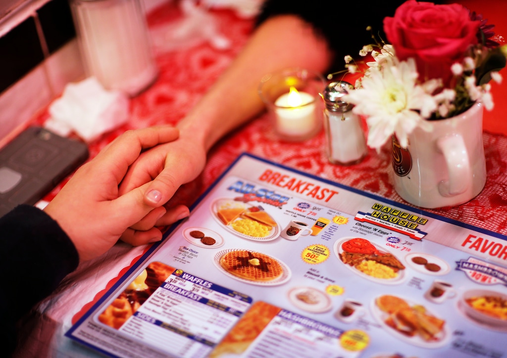 (David Goldman | The Associated Press) Valerie Deschamps-Goren, right, holds hands with Basil Gravanis while dining at a Waffle House restaurant decorated for Valentine's Day in Atlanta, Wednesday, Feb. 14, 2018. The famous Southern diner chain creates a romantic atmosphere with soft music, white tablecloths, and candlelight dinner in 170 of their restaurants for the annual holiday.