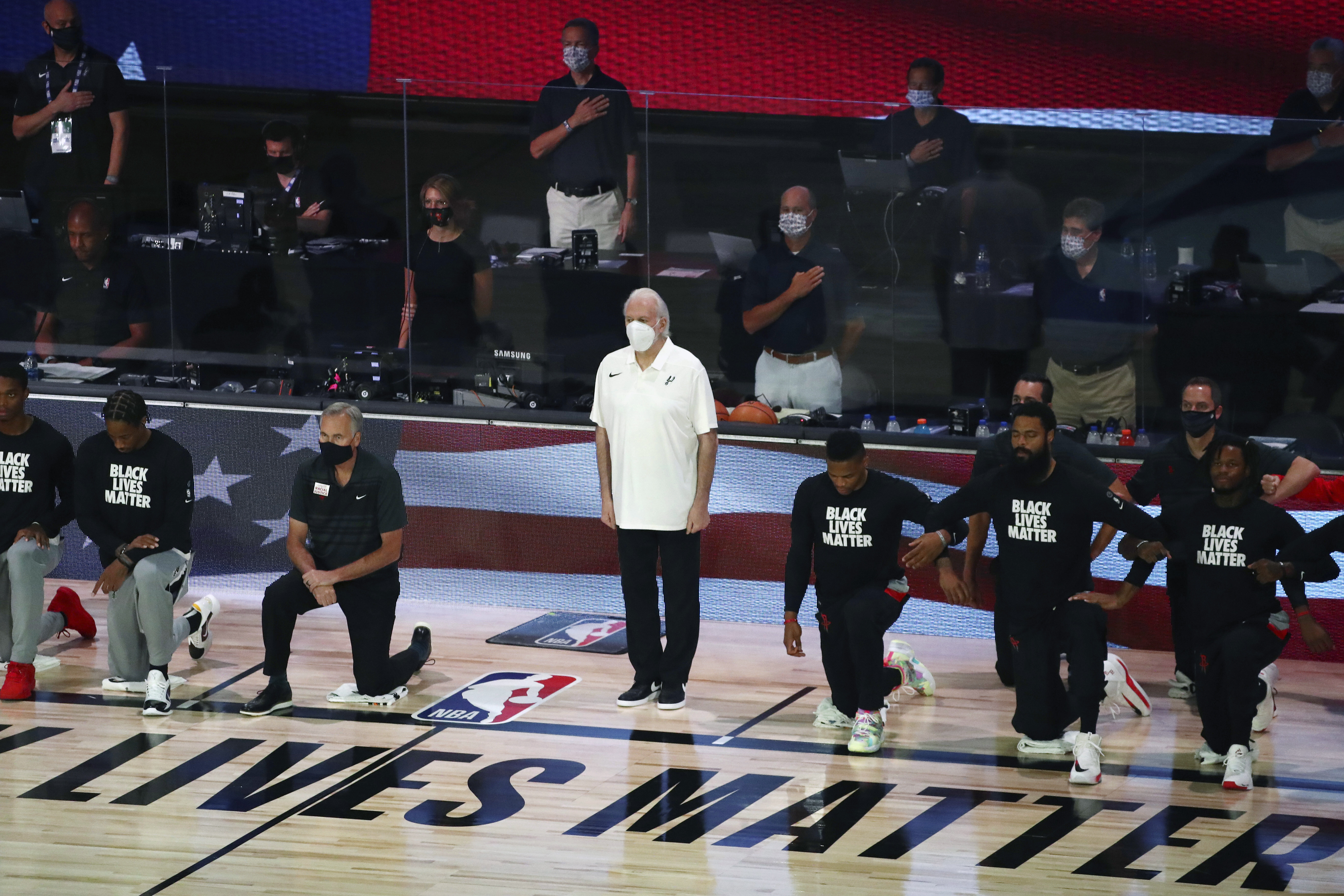 (Kim Klement | Pool photo via AP)  San Antonio Spurs head coach Gregg Popovich, standing at center, wears a mask while players kneel before an NBA basketball game against the Houston Rockets, Tuesday, Aug. 11, 2020, in Lake Buena Vista, Fla.