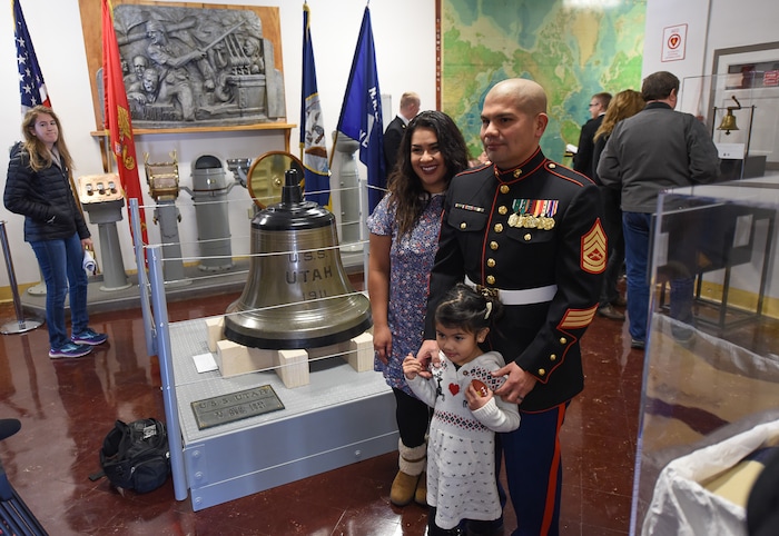 (Francisco Kjolseth  |  The Salt Lake Tribune)  Gunnery Sergeant Levi Lazaro, joined by his wife Marlene and daughter Elissa, 4, pose for a photograph alongside the newly restored bell from the USS Utah now on display at the Naval Science building at the University of Utah.  