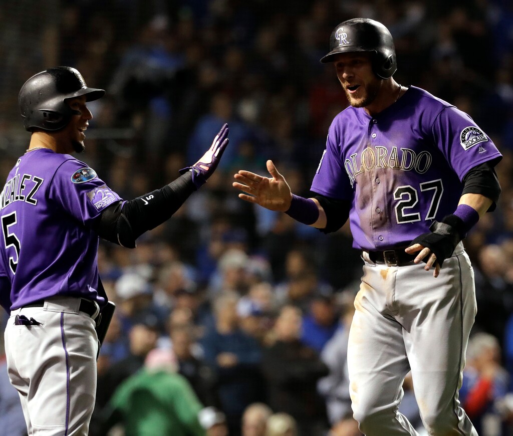 Colorado Rockies' Trevor Story, right, celebrates with Carlos Gonzalez after scoring on a one-run single by Tony Wolters during the 13th inning of the National League wild-card playoff baseball game against the Chicago Cubs, Tuesday, Oct. 2, 2018, in Chicago. (AP Photo/Nam Y. Huh)