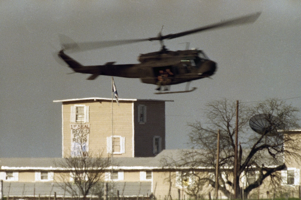 (AP Photo/David Philip) A helicopter makes a low pass over a banner that was unfurled from a window by Branch Davidian cult members at the compound near Waco, Texas on Friday, April 9, 1993.