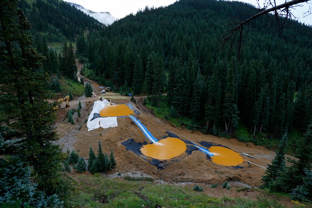 FILE--In this Aug. 12, 2015, file photo, mine wastewater flows through a series of retention ponds built to contain and filter out heavy metals and chemicals from the Gold King Mine chemical accident in the spillway about 1/4 mile downstream from the mine, outside Silverton, Colo. Crumbling mine tunnels awash with polluted waters perforate the Colorado mountains, and scientists may one day send robots creeping through the pitch-black passages to study the mysterious currents that sometimes burst to the surface with devastating effects. (AP Photo/Brennan Linsley, file)