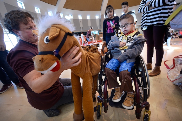 (Scott Sommerdorf | The Salt Lake Tribune)
Luis Angel Flores, 5 years old, is introduced to the horse that will be attached to his wheelchair by volunteer Scott Jerome. Shriners Hospitals for Children volunteers transformed the wheelchairs of 20 patients for Halloween, Wednesday, October 18, 2017.