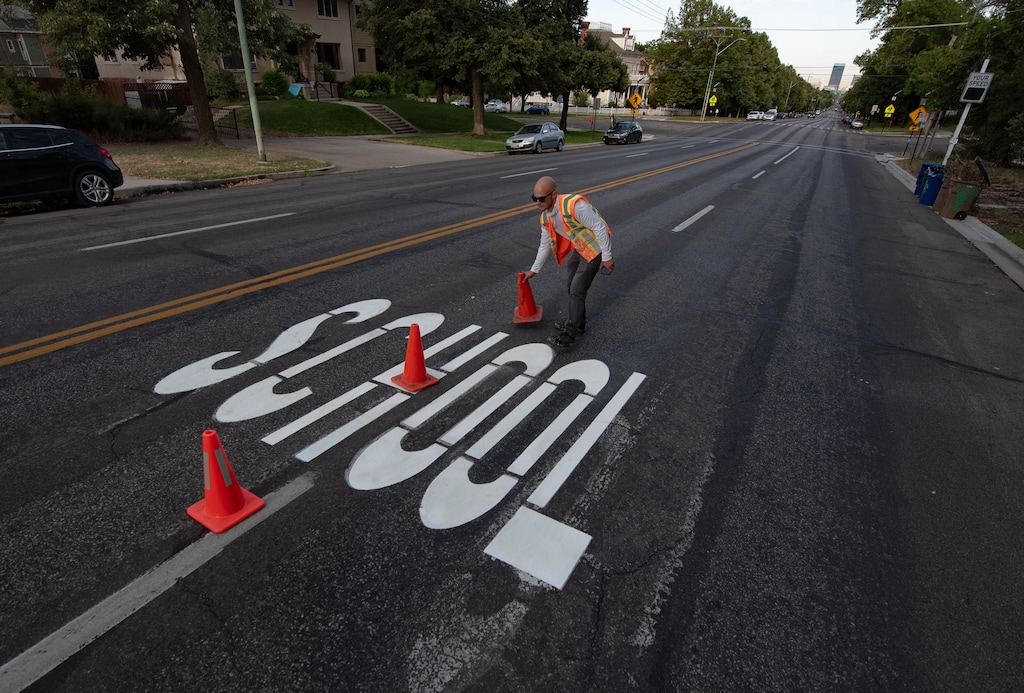 (Francisco Kjolseth  |  The Salt Lake Tribune) Andrew Hainsworth with Salt Lake City Public Services removes traffic cones after letting the paint dry on a school sign near downtown on Monday, July 27, 2020, as students face an uncertain reopening plans due to the coronavirus pandemic.